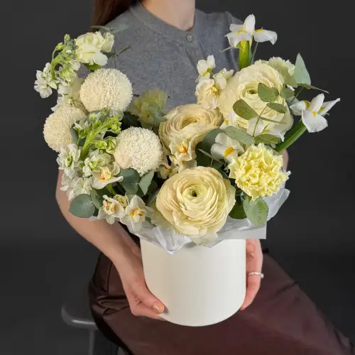 Цветочная композиция из ранункулюсов, ирисов и нарциссов в шляпной коробке